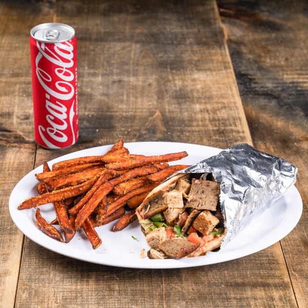A gyro wrap with sweet potato fries and a Coca-Cola can on a white plate.